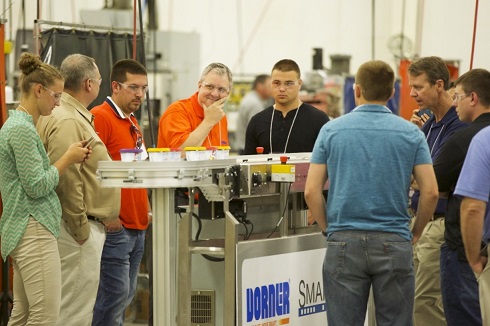 group of professionals on Dorner tour surrounded around a conveyor belt