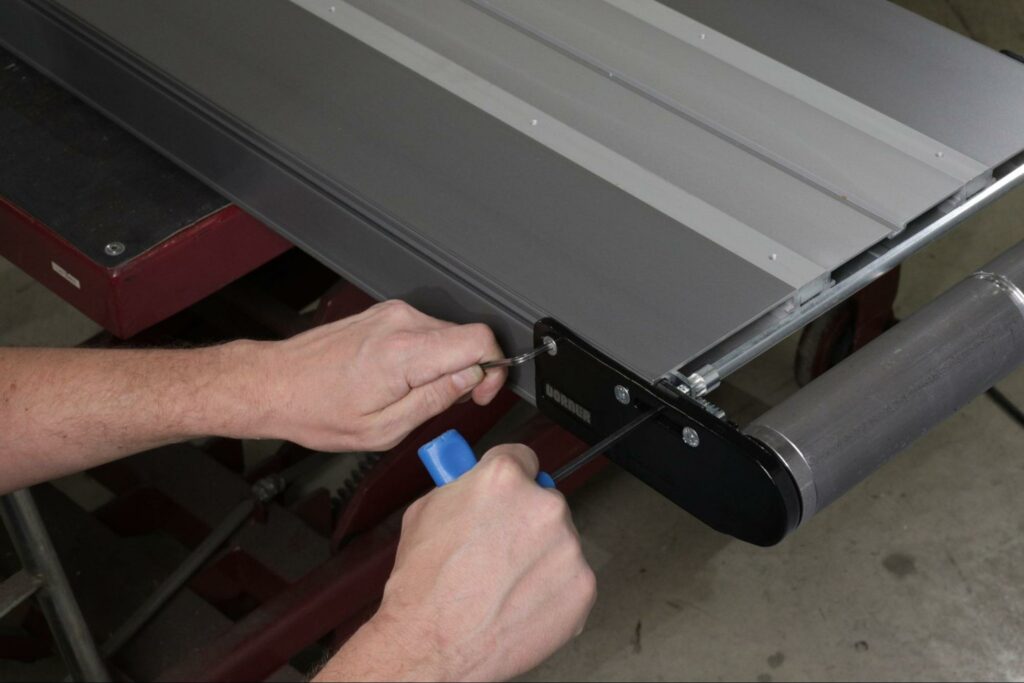 An operator adjusts the belt tension on a Dorner conveyor.