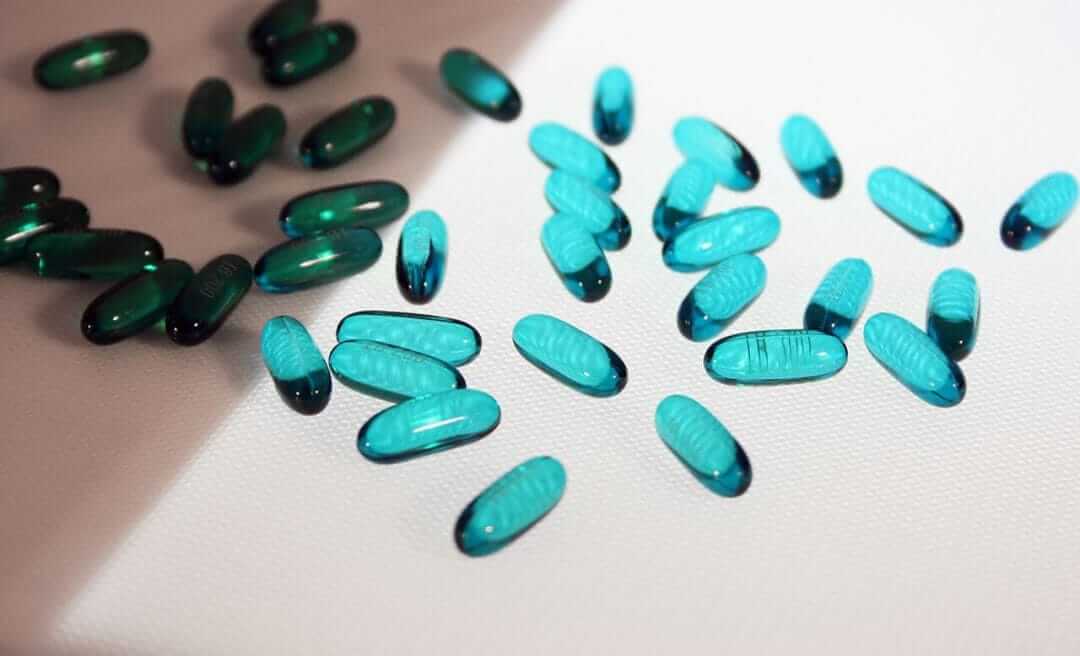 A number of loose blue pills passing over an illuminated section of a Dorner conveyor.