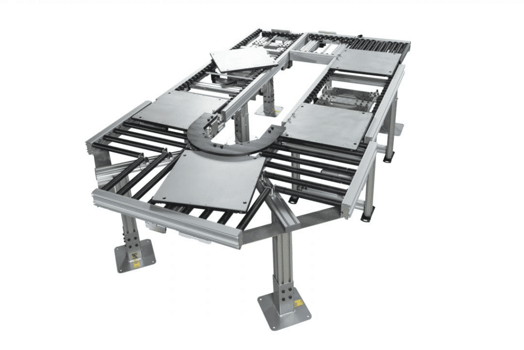 Full view of a complex ERT conveyor system. It has multiple tracks and a curved section, demonstrating the flexibility and modularity of the system. This layout would allow for different stages of production or testing to occur at various points along the conveyor path.